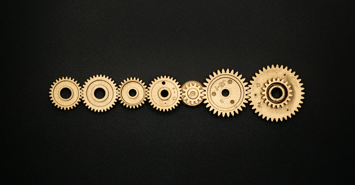Interlocked golden (bronze) gears in a perfect line on a black background.