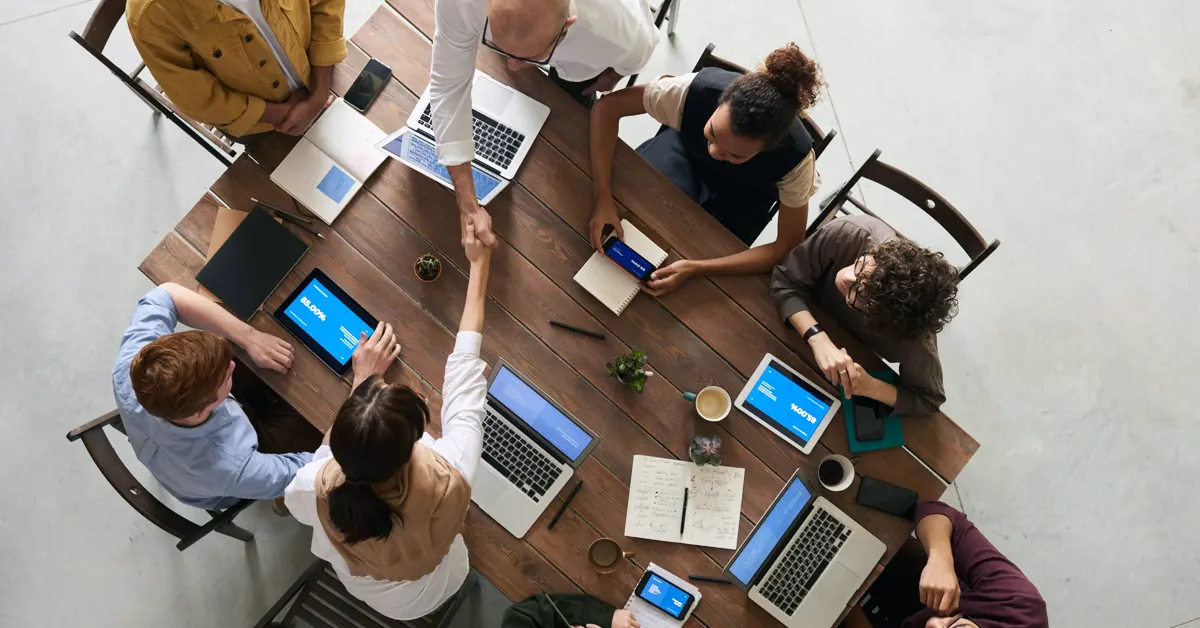 Employees sitting around a wooden office table.