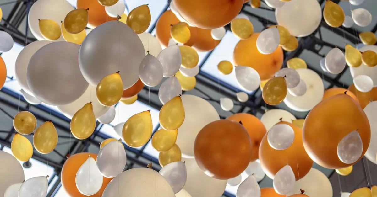 Helium-filled balloons float among confetti