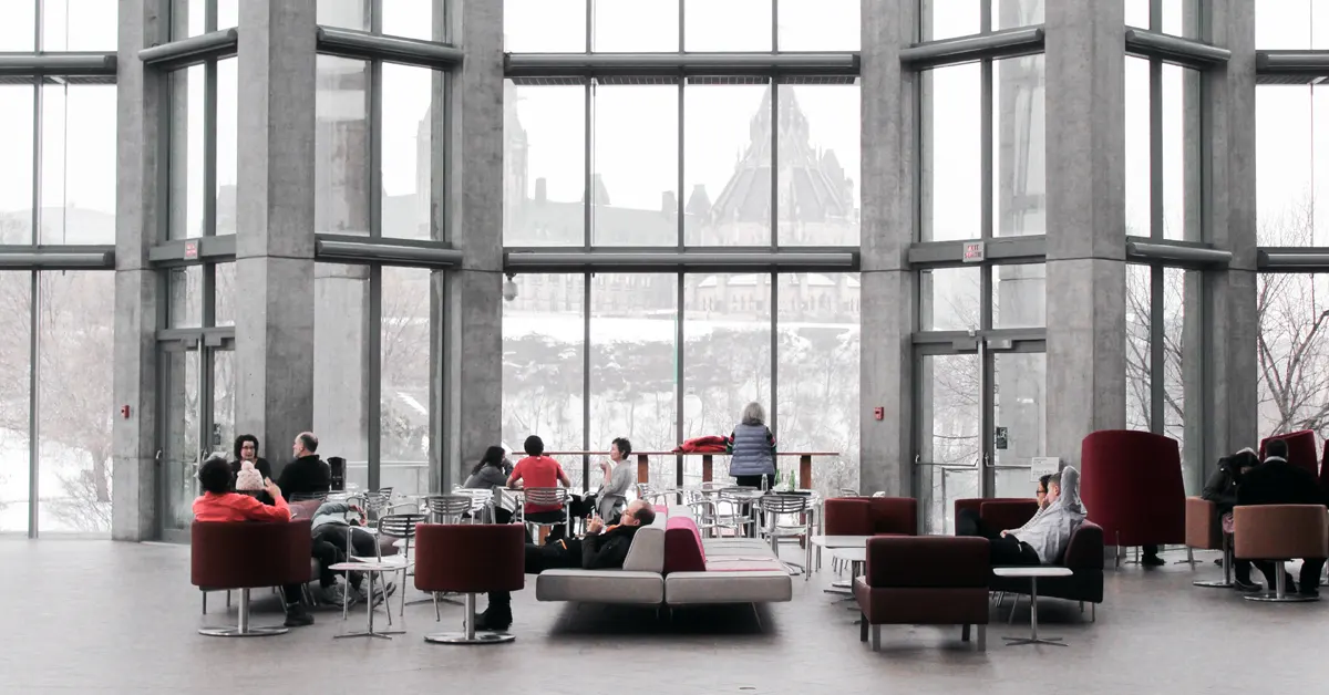 A lobby is filled with many repeat guests sitting and standing.