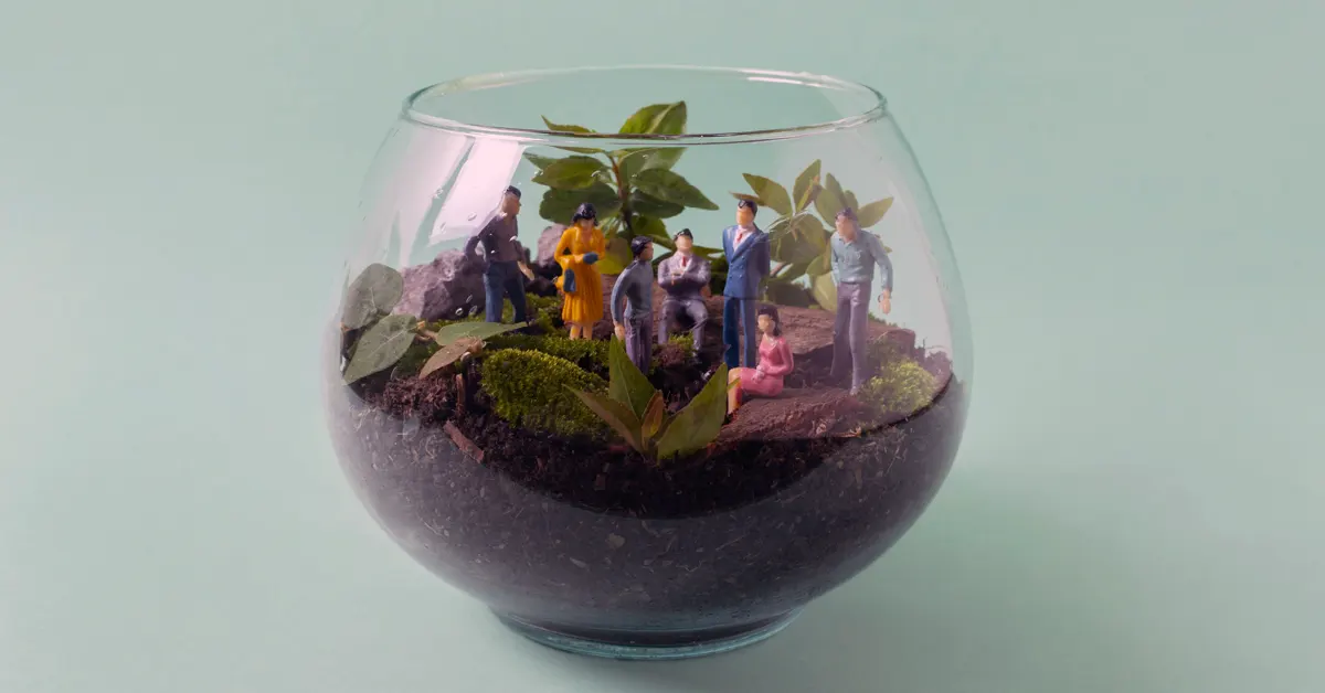 Small plastic figurines in suits and ties in a glass.